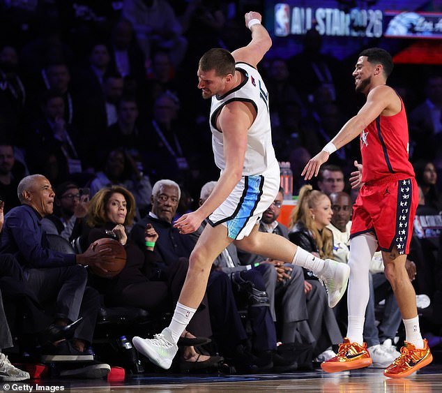 Obama atrapa un balón suelto mientras está sentado en la cancha con Michelle durante el juego All Star de la NBA.