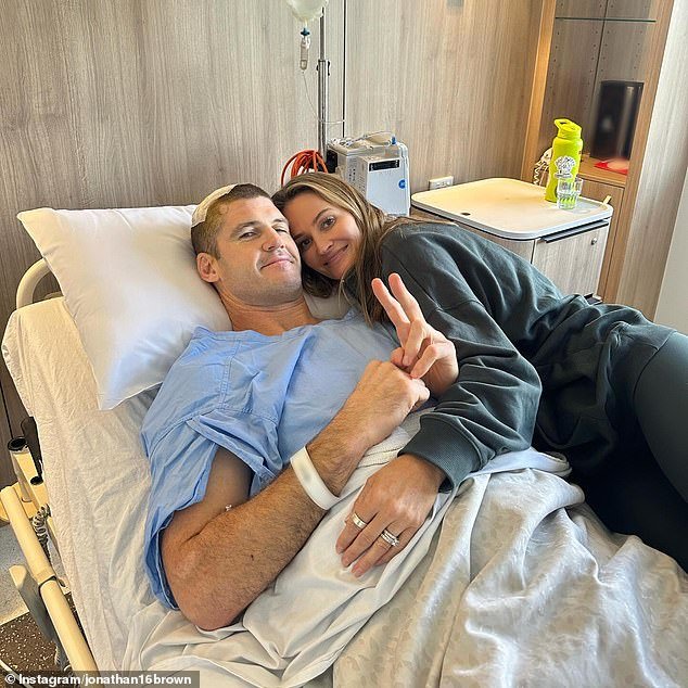 La leyenda del fútbol Jonathan Brown, de 44 años, es consolada por su esposa en el hospital después de una cirugía cerebral, mientras revela cómo una exploración de rutina reveló un tumor.