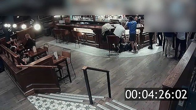 Momento en el que dos ladrones descarados registran tranquilamente las bolsas de los clientes de un pub mientras conversan cerca